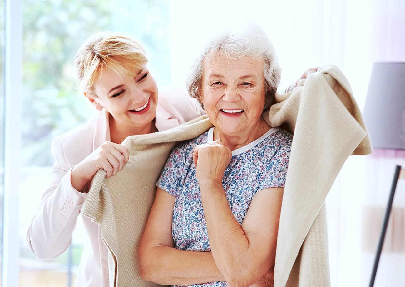 caregiver giving a blanket to senior woman