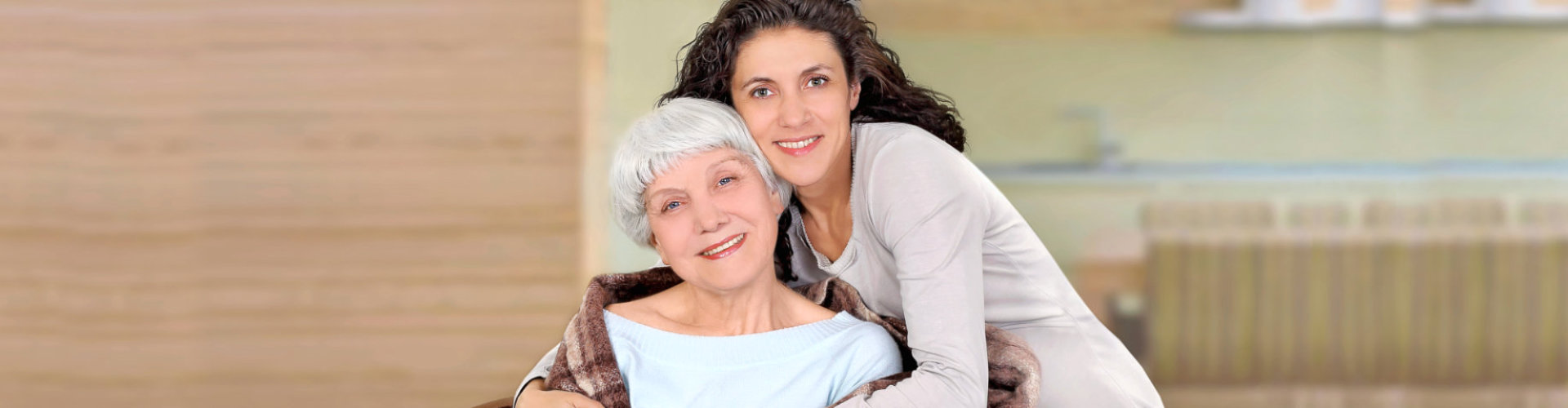 caregiver and senior woman are smiling while hugging